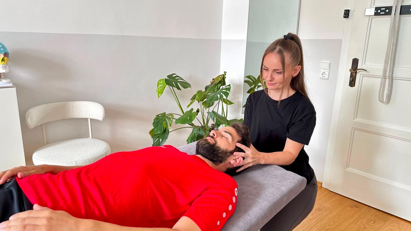 Michaela Schumacher bei einer craniosakralen Behandlung am Kopf eines liegenden Sportlers.