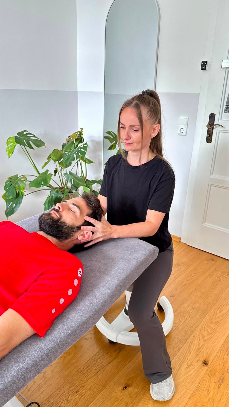 Michaela Schumacher bei einer craniosakralen Behandlung am Kopf eines Sportlers.